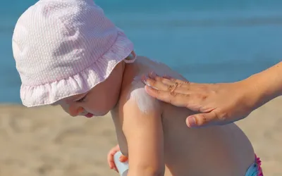 une maman appliquant une creme de protection à son bebe sur la plage